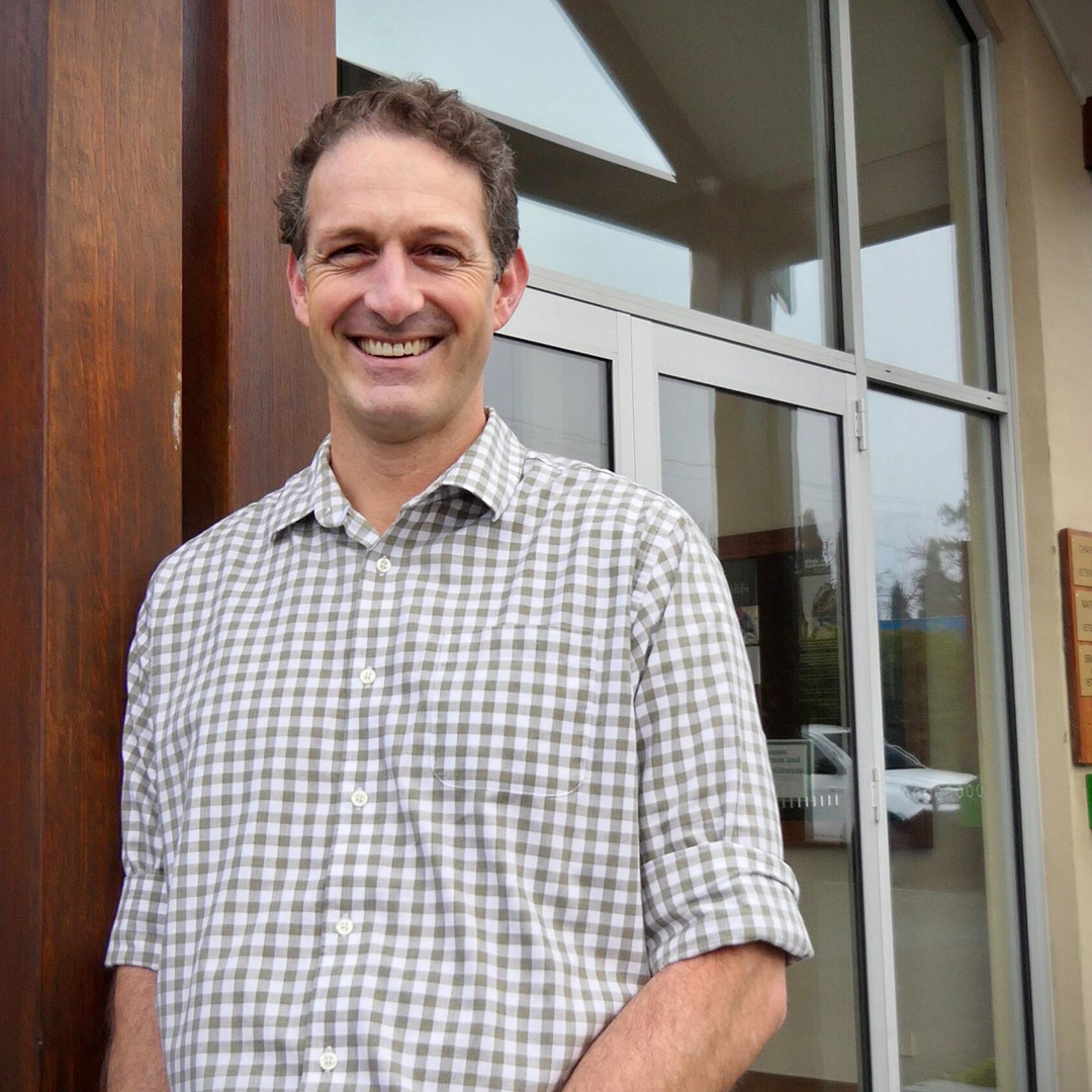 Charlie Carter, owner and veterinarian at Southern Highlands Veterinary Centre, standing outside the clinic wearing a green uniform and smiling.